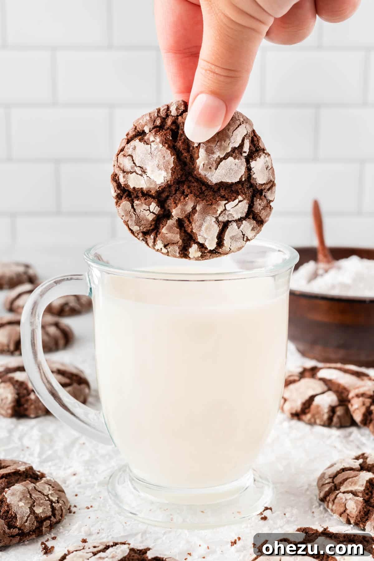 Chocolate crinkle cookie being dipped into a glass of milk