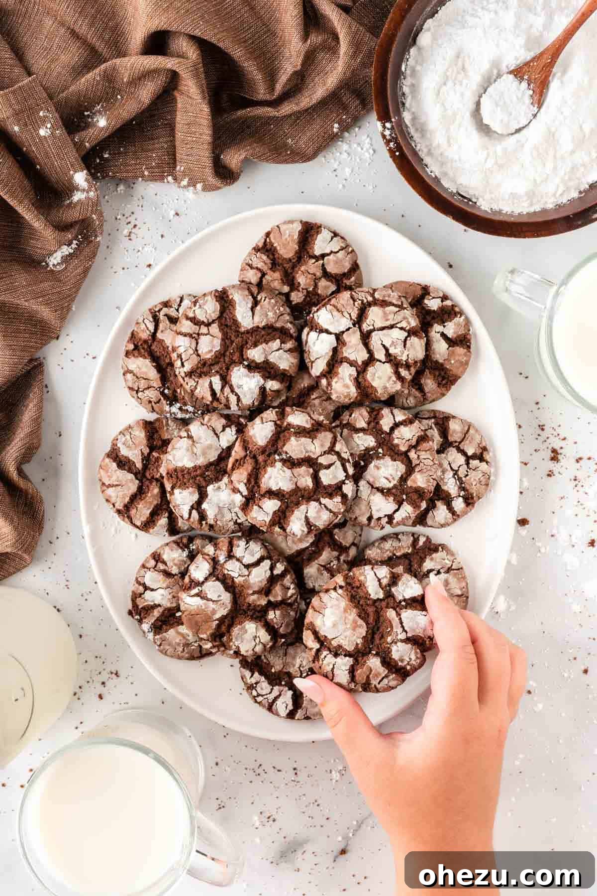Someone taking a crinkle cookie from a white platter
