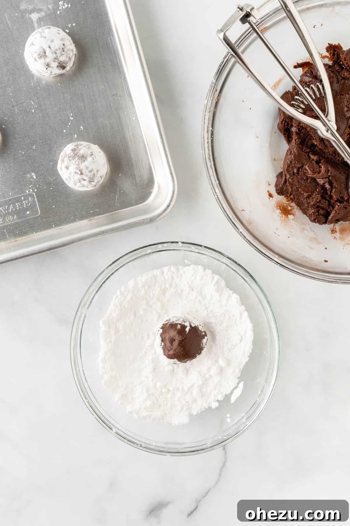 Rolling a ball of chocolate cookie dough in powdered sugar