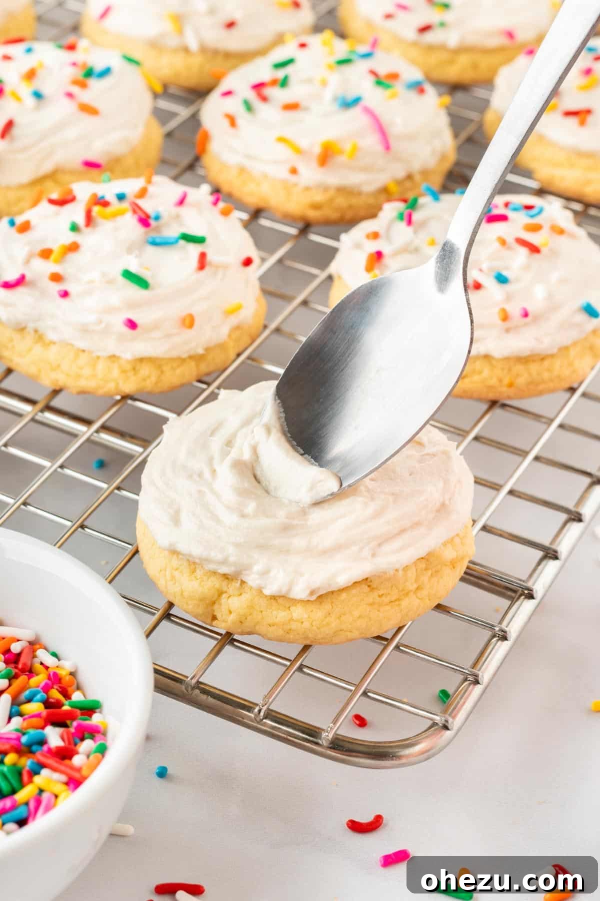 topping the sugar cookies with frosting using a spatula