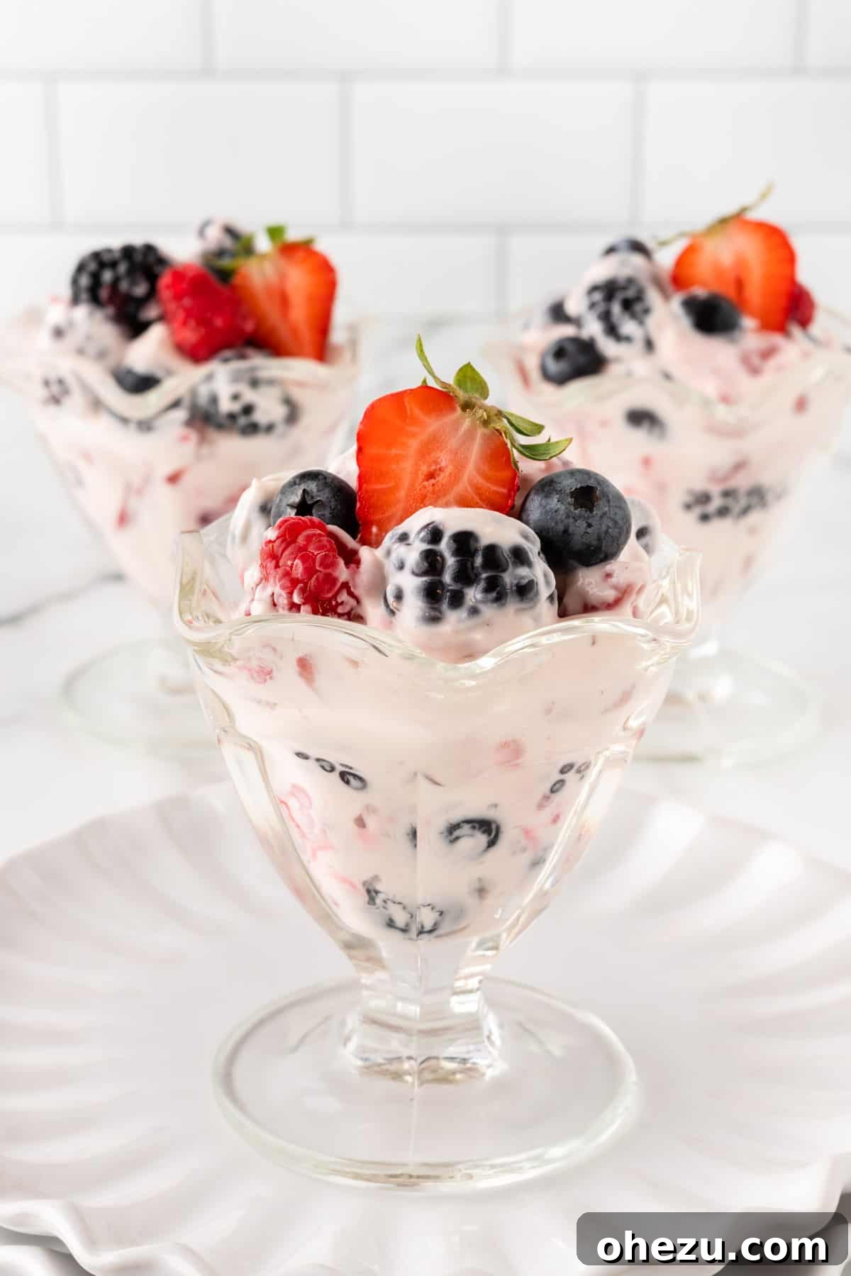 Individual parfait cups filled with berry cheesecake salad, showcasing layers of creamy filling and fresh berries, ready for guests.