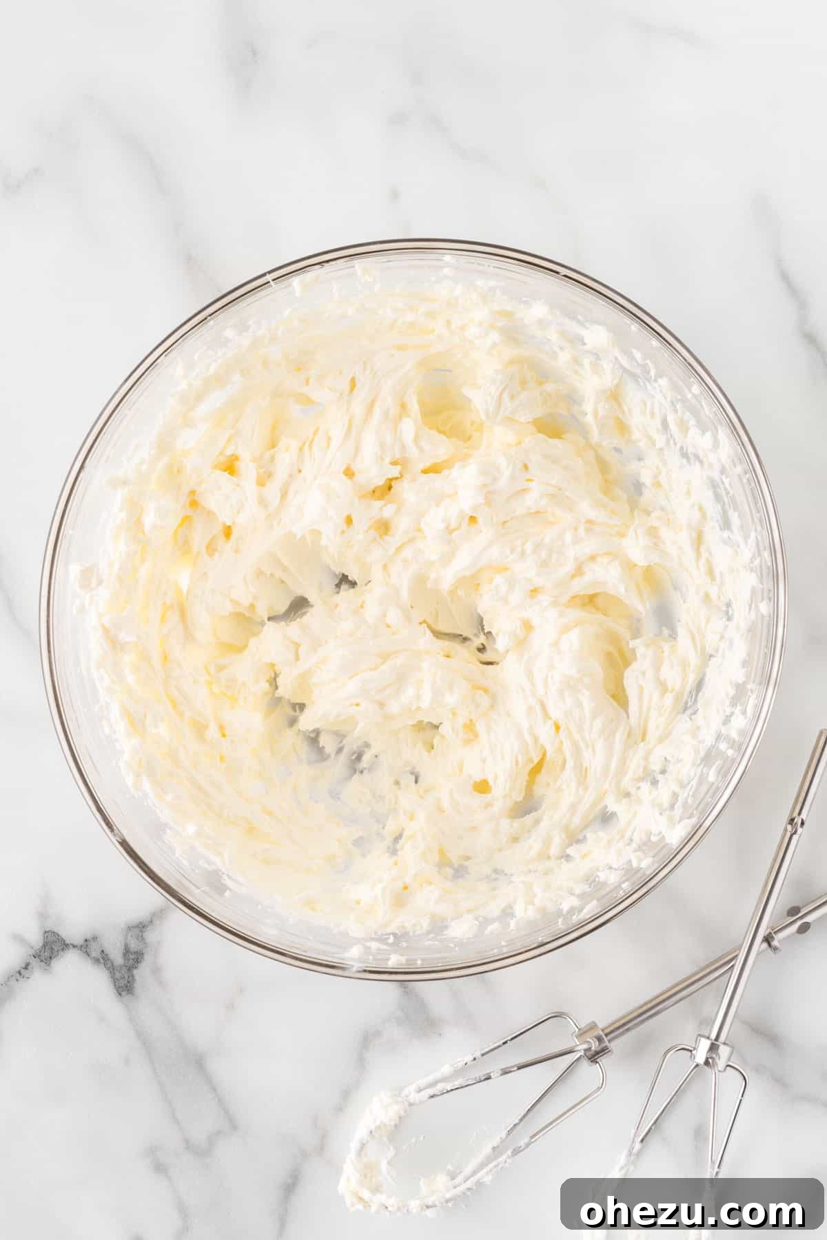 A bowl of freshly beaten cream cheese, smooth and ready to be mixed into the filling.