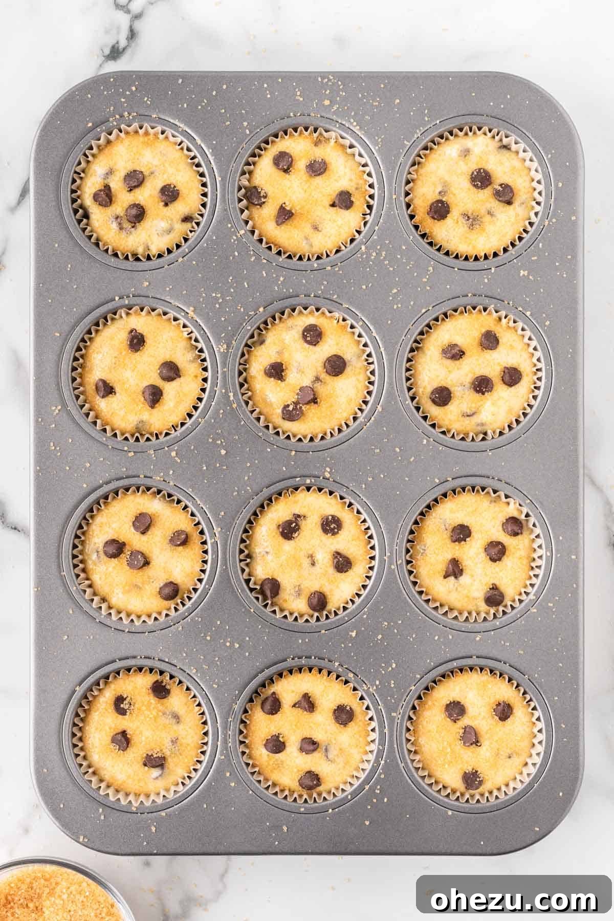 Irresistible Bakery Chocolate Chip Muffins 13 Adding coarse sugar to the tops of the muffin batter