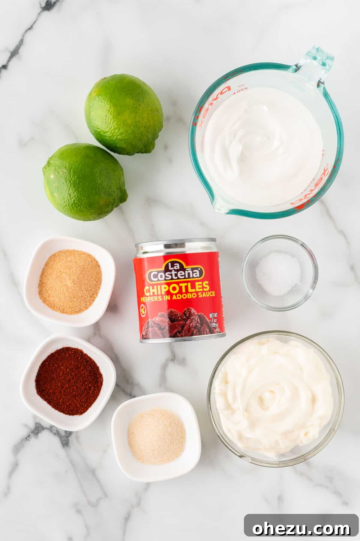 Close-up of fresh ingredients for chipotle ranch dressing, including sour cream, mayonnaise, lime, garlic, and chipotle peppers.