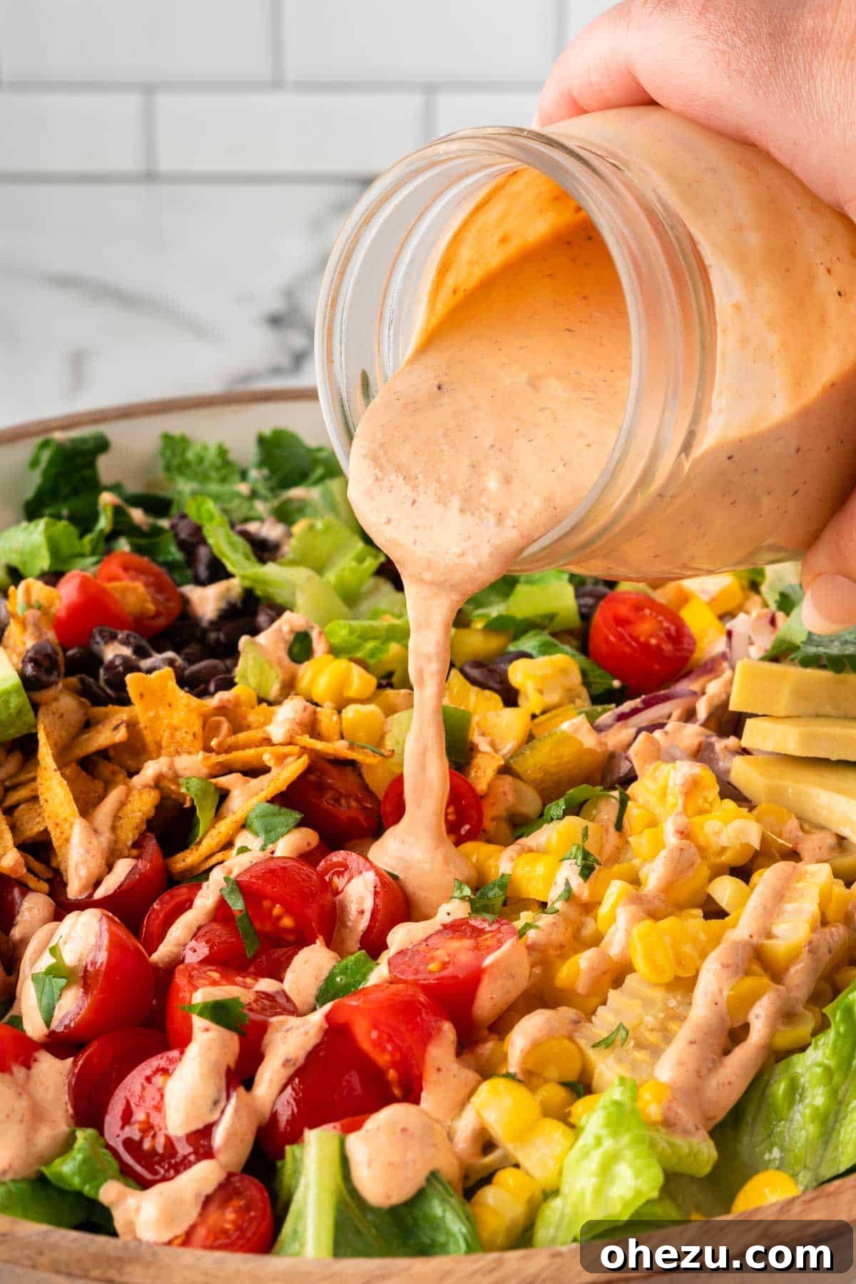 Smooth and creamy homemade chipotle ranch dressing being drizzled over a vibrant mixed green salad, ready to be enjoyed.