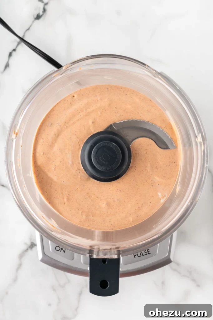Chipotle ranch dressing being blended to a smooth, creamy consistency in a food processor.