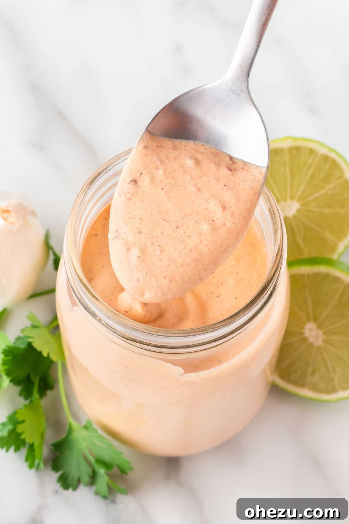 A mason jar filled with creamy chipotle ranch dressing, with a wooden spoon dipped in it, showcasing its rich texture.