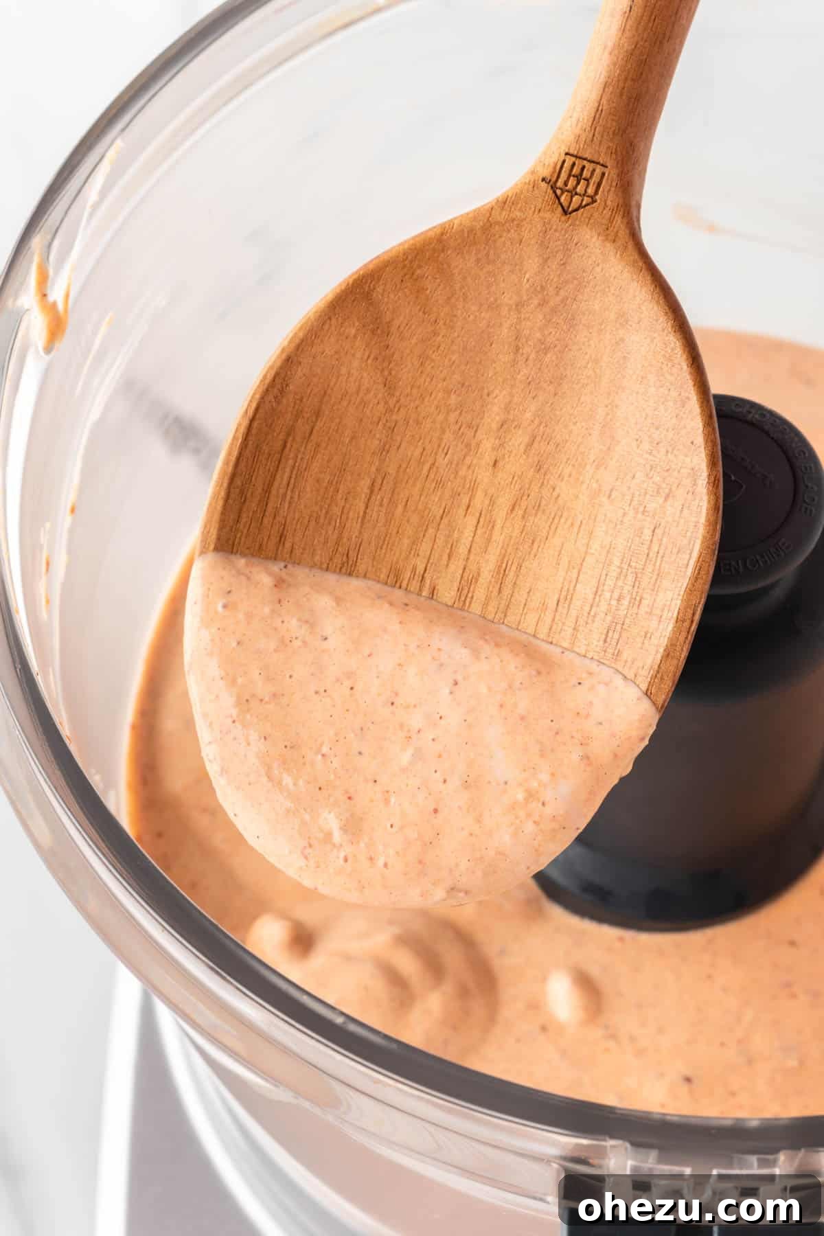 A wooden spoon scooping creamy southwest salad dressing, highlighting its smooth and thick texture.