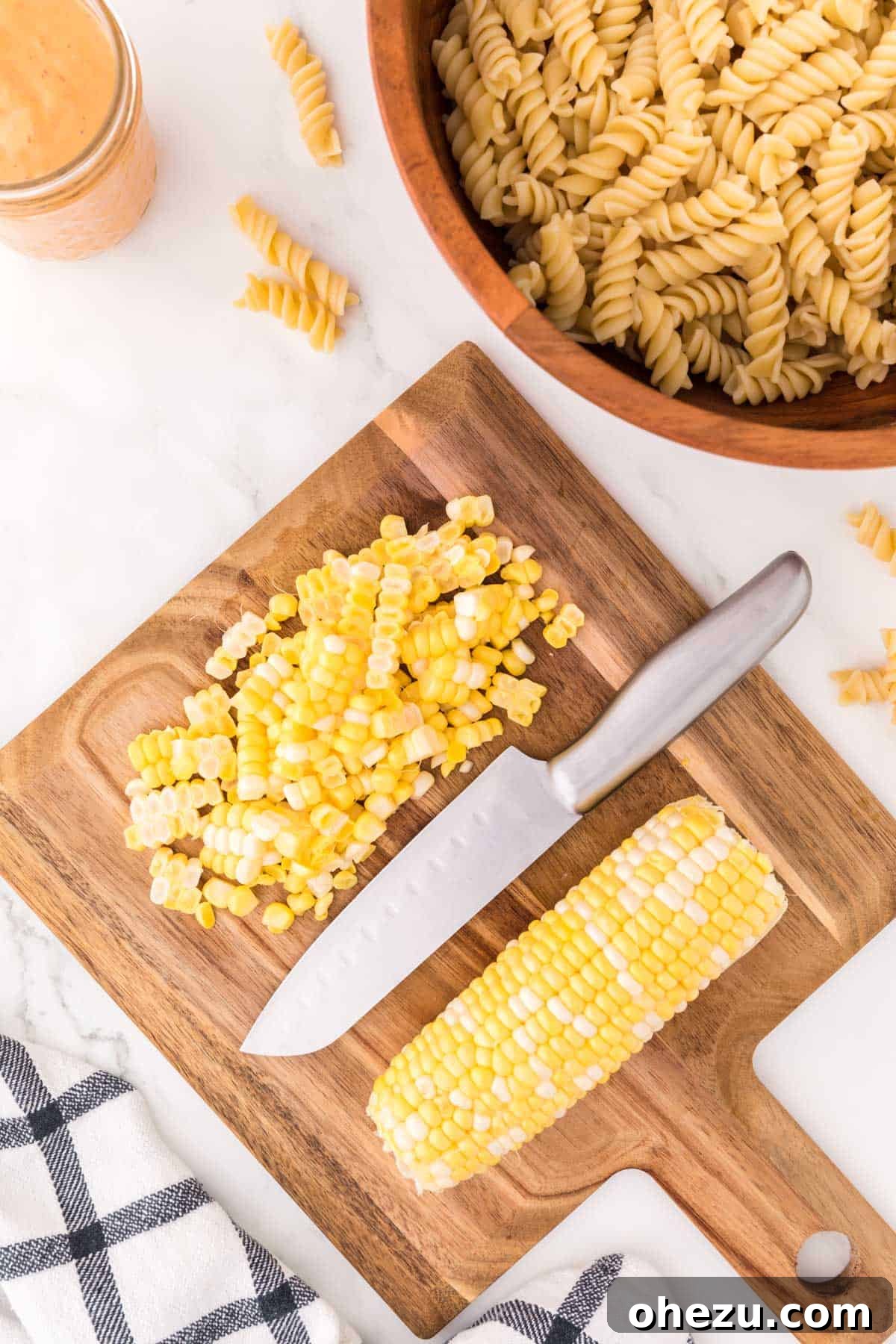 Zesty Fiesta Pasta Salad 5 Fresh corn kernels neatly cut from the cob and arranged on a wooden cutting board, ready for the pasta salad.