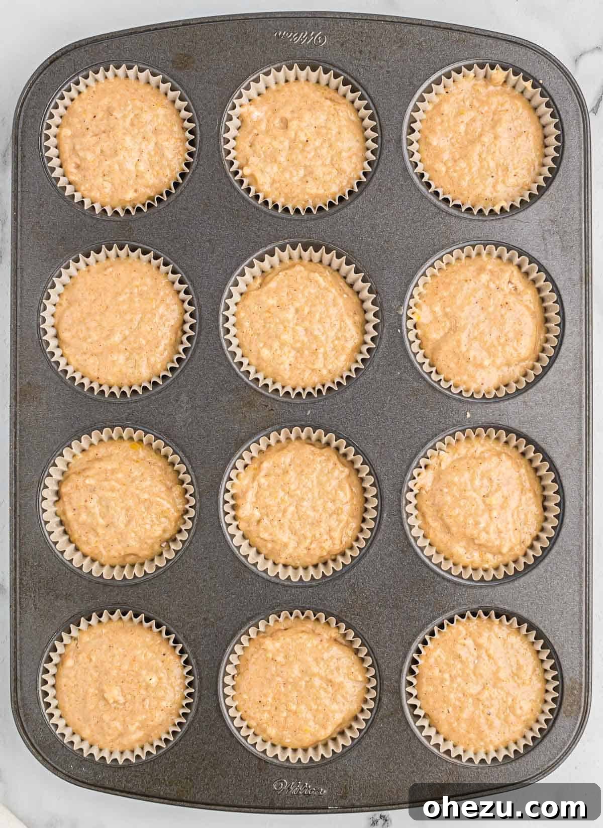 Cinnamon Apple Muffins 9 Applesauce muffin batter scooped into a 12-cup muffin tin with paper liners