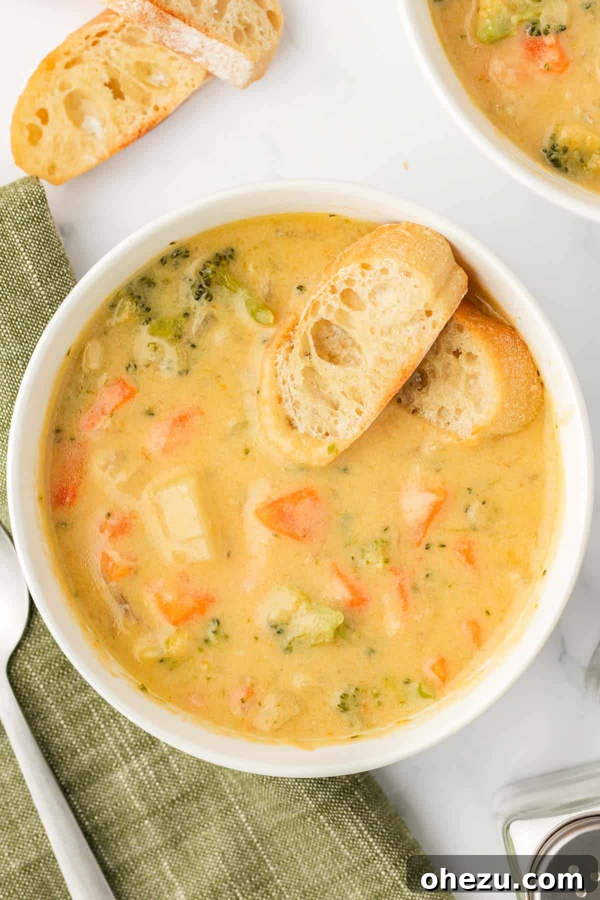 A steaming bowl of creamy vegetable soup served with crusty baguette slices, ready to be enjoyed as the ultimate comfort food.