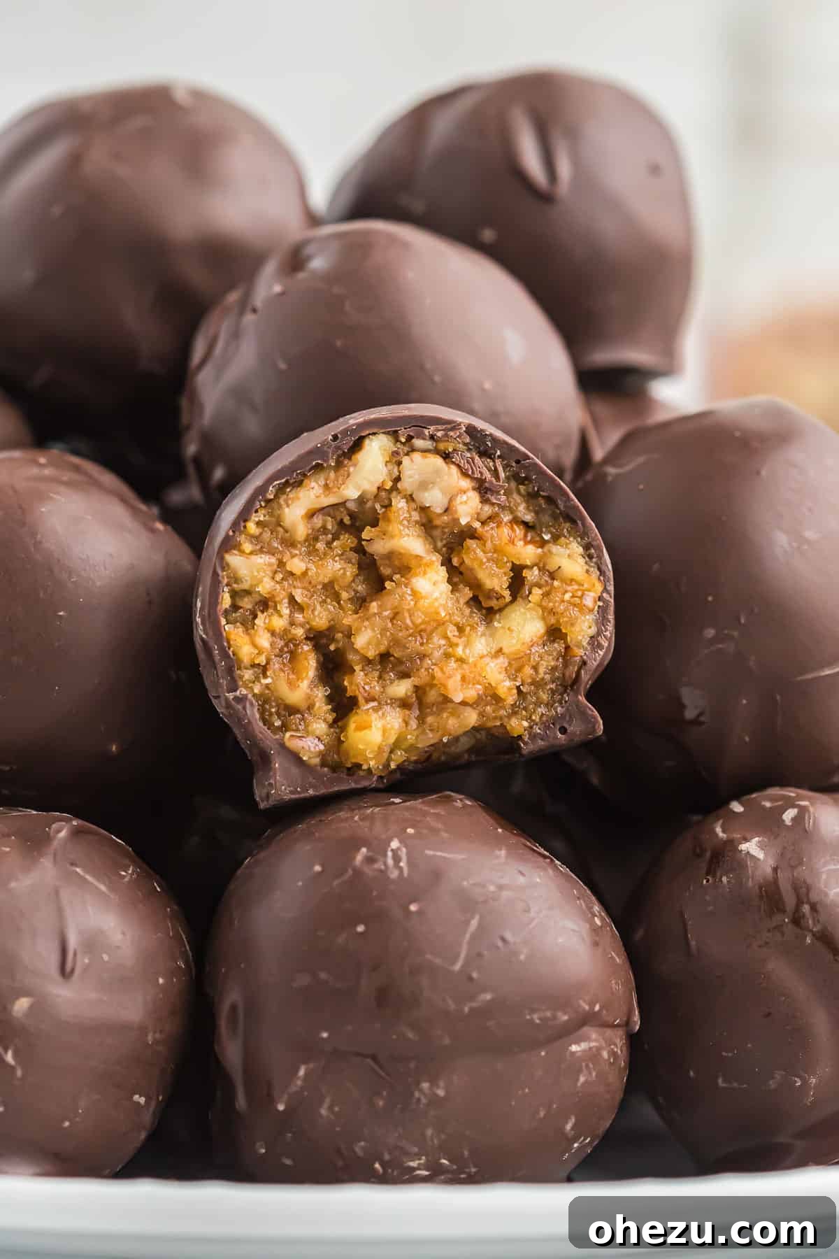Pecan Pie Truffles 2 A delicious no bake pecan pie ball with a bite taken out, showing the gooey pecan filling and chocolate coating