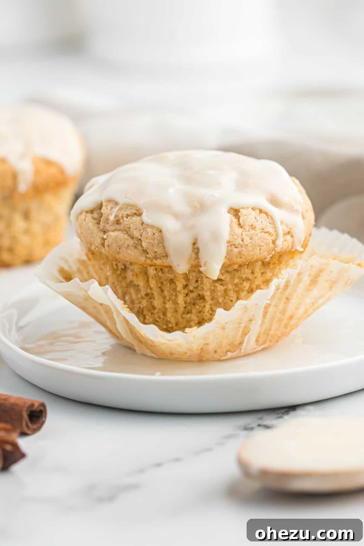 A single glazed eggnog muffin on a white plate, ready to be enjoyed.