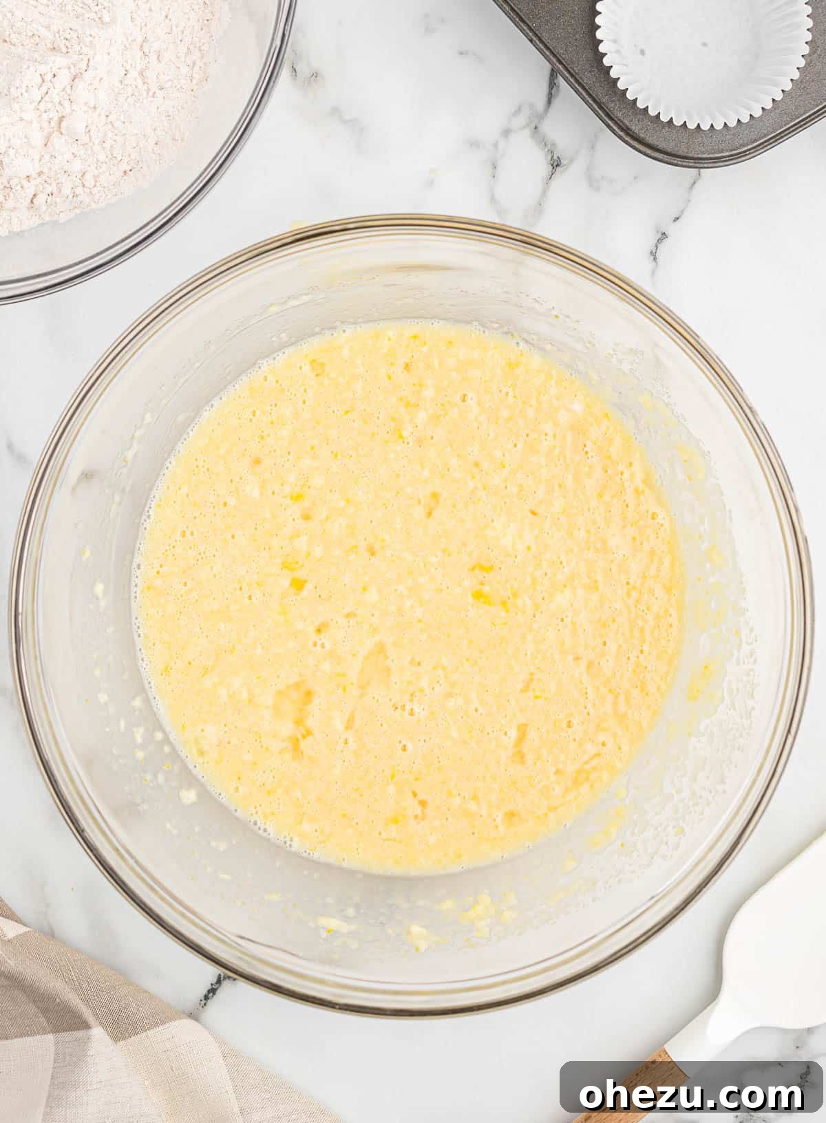 Wet ingredients for eggnog muffins, including eggnog, eggs, sugar, vanilla, and melted butter, in a mixing bowl.