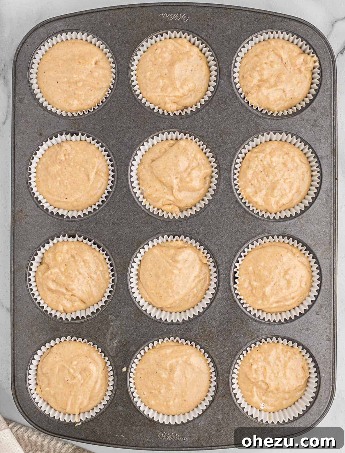 Muffin tin filled with eggnog batter, ready to be baked.