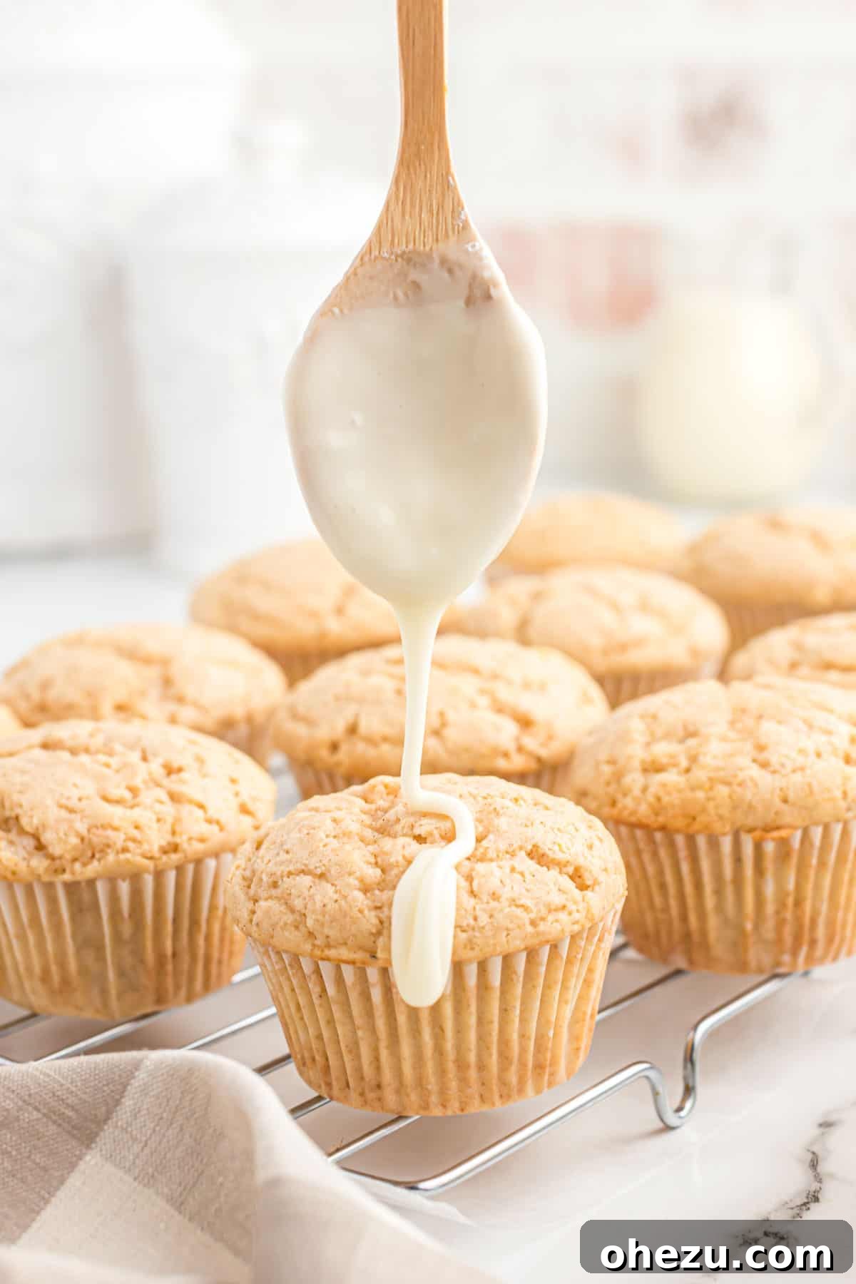 Hand glazing freshly baked eggnog muffins with a smooth eggnog icing.