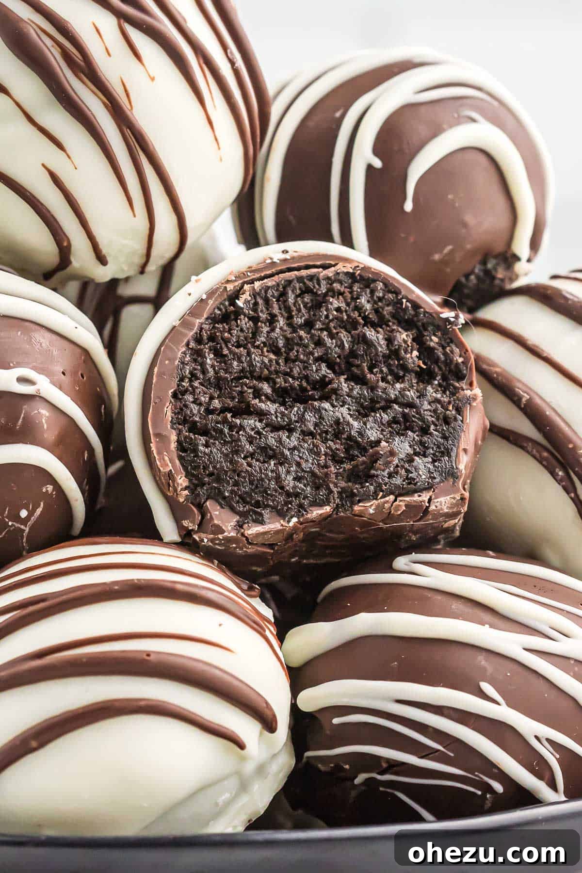 A close-up of an oreo truffle with a bite taken out, revealing its rich, creamy interior.
