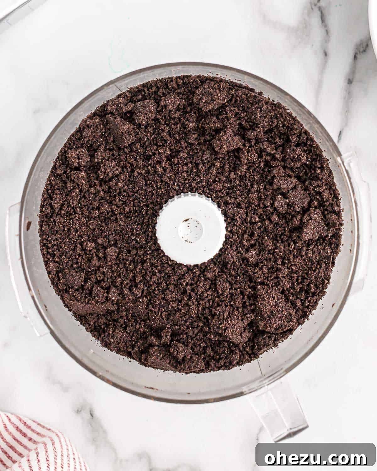 Oreo cookies crushed into fine crumbs in a food processor, ready for the next step of the recipe.