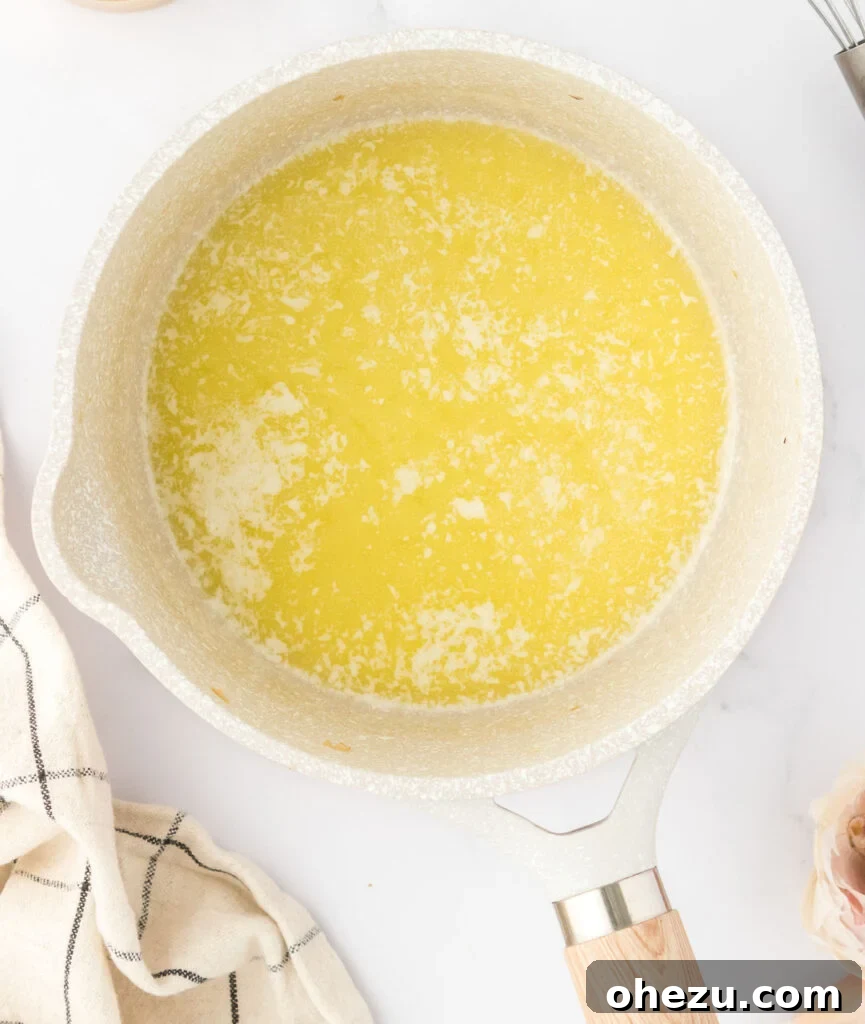 The remaining six tablespoons of butter melting in a saucepan, forming a clear liquid base for the roux.
