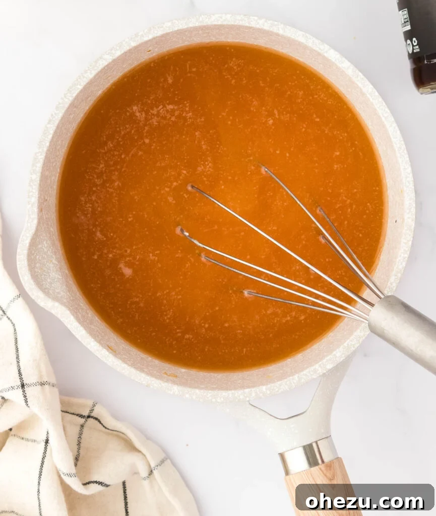 Pouring vegetable broth into a saucepan containing the prepared roux, while whisking continuously to prevent lumps.