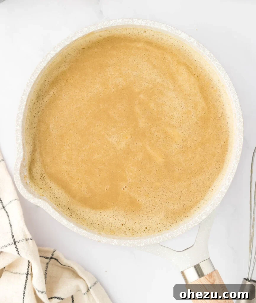 Smooth vegetarian gravy simmering gently in a saucepan, thickening gradually to a rich consistency.