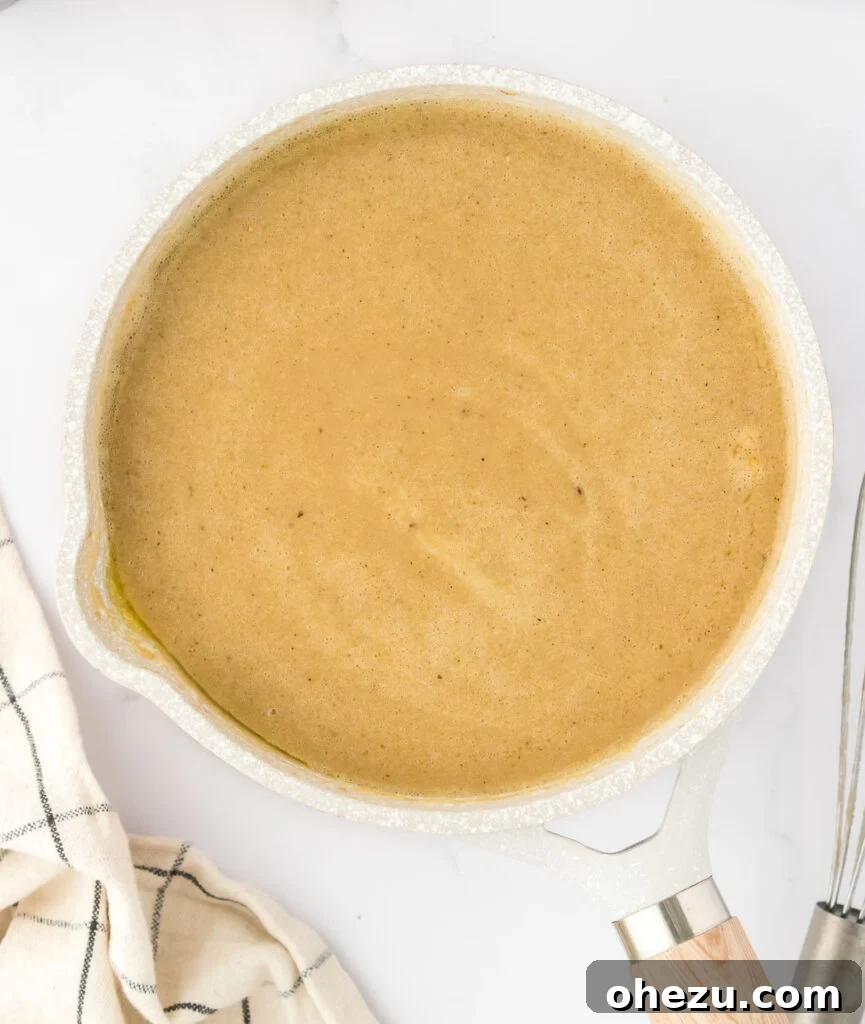 Finished vegetarian gravy, thick, rich, and perfectly seasoned, ready to be served from a saucepan.