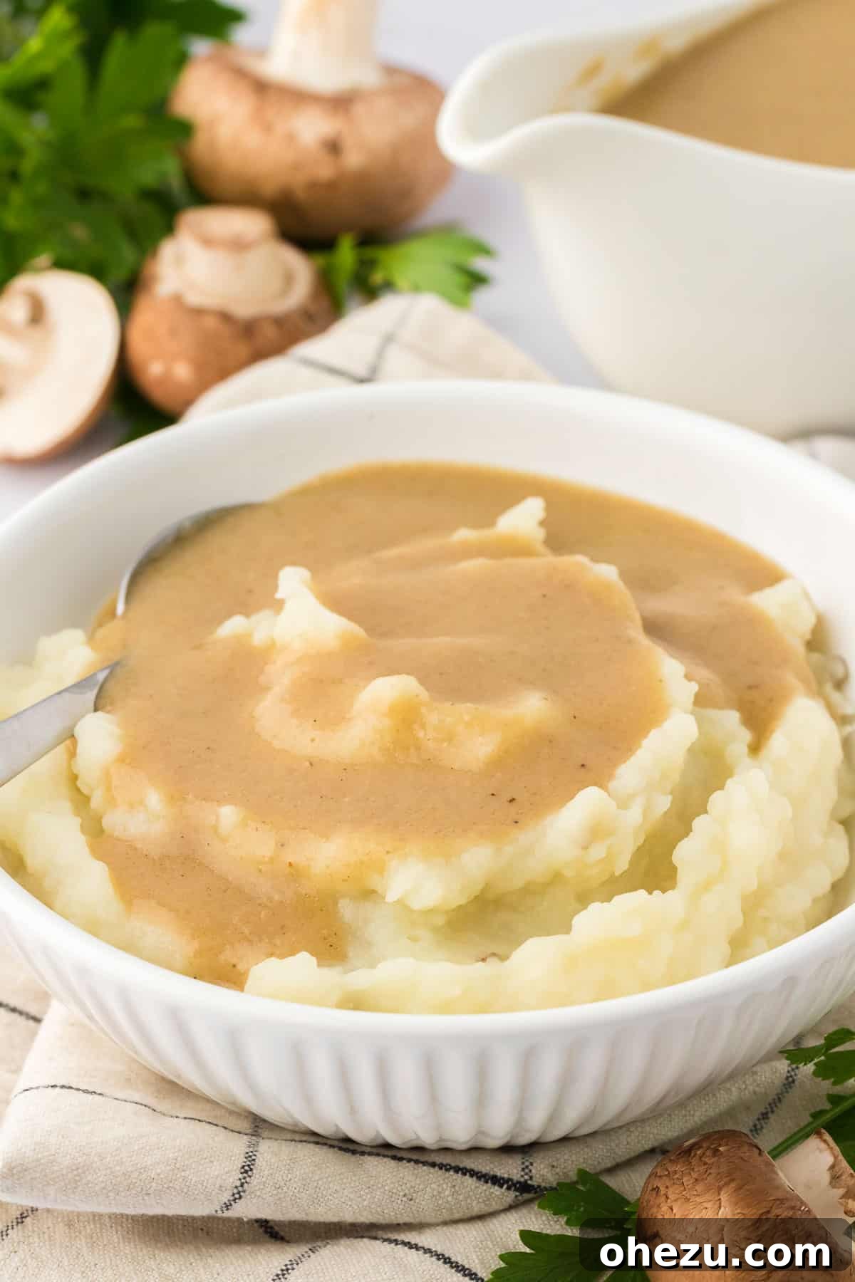 Creamy vegetarian gravy generously drizzled over a mound of golden mashed potatoes in a white bowl, ready to be enjoyed.