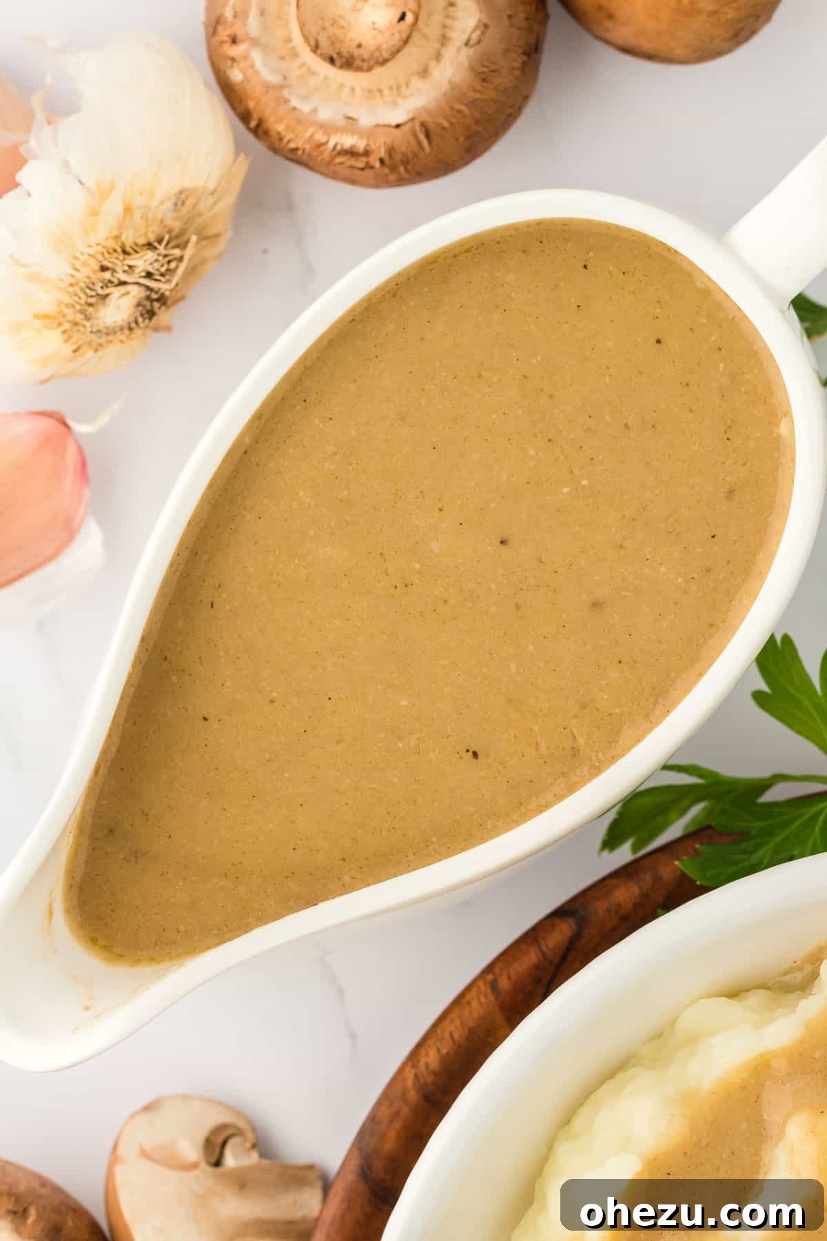 A beautifully textured and rich vegetarian gravy glistening in a classic white ceramic gravy boat, perfectly presented for serving at a holiday meal.