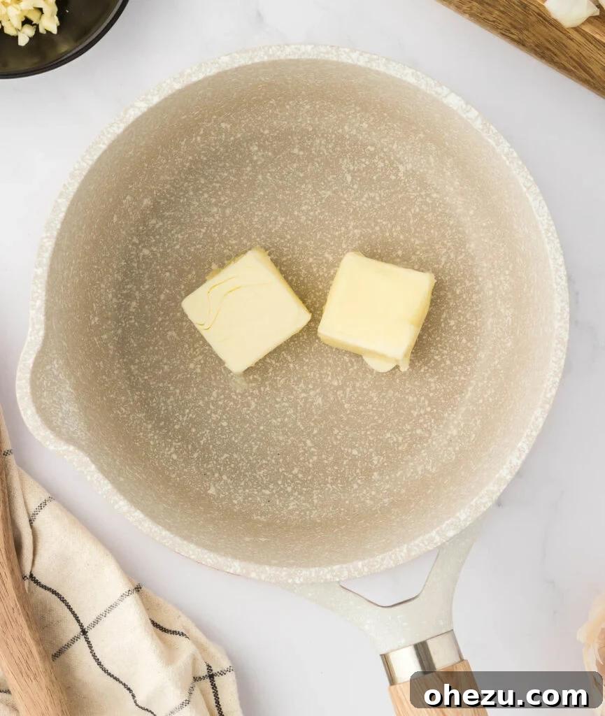 Two tablespoons of butter melting in a hot saucepan, preparing the base for the vegetarian gravy.