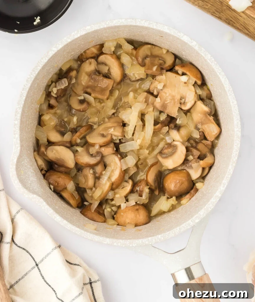 The fully cooked mushroom, garlic, and onion mixture, softened and reduced, in a saucepan after sautéing.