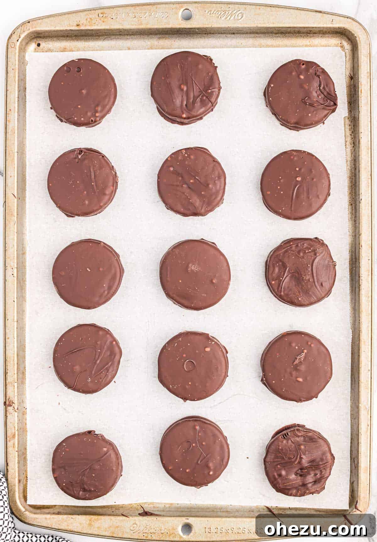 Decadent Oreo Delights 6 A tray of chocolate-dipped Oreos, freshly coated and arranged on a baking sheet, waiting to be chilled.