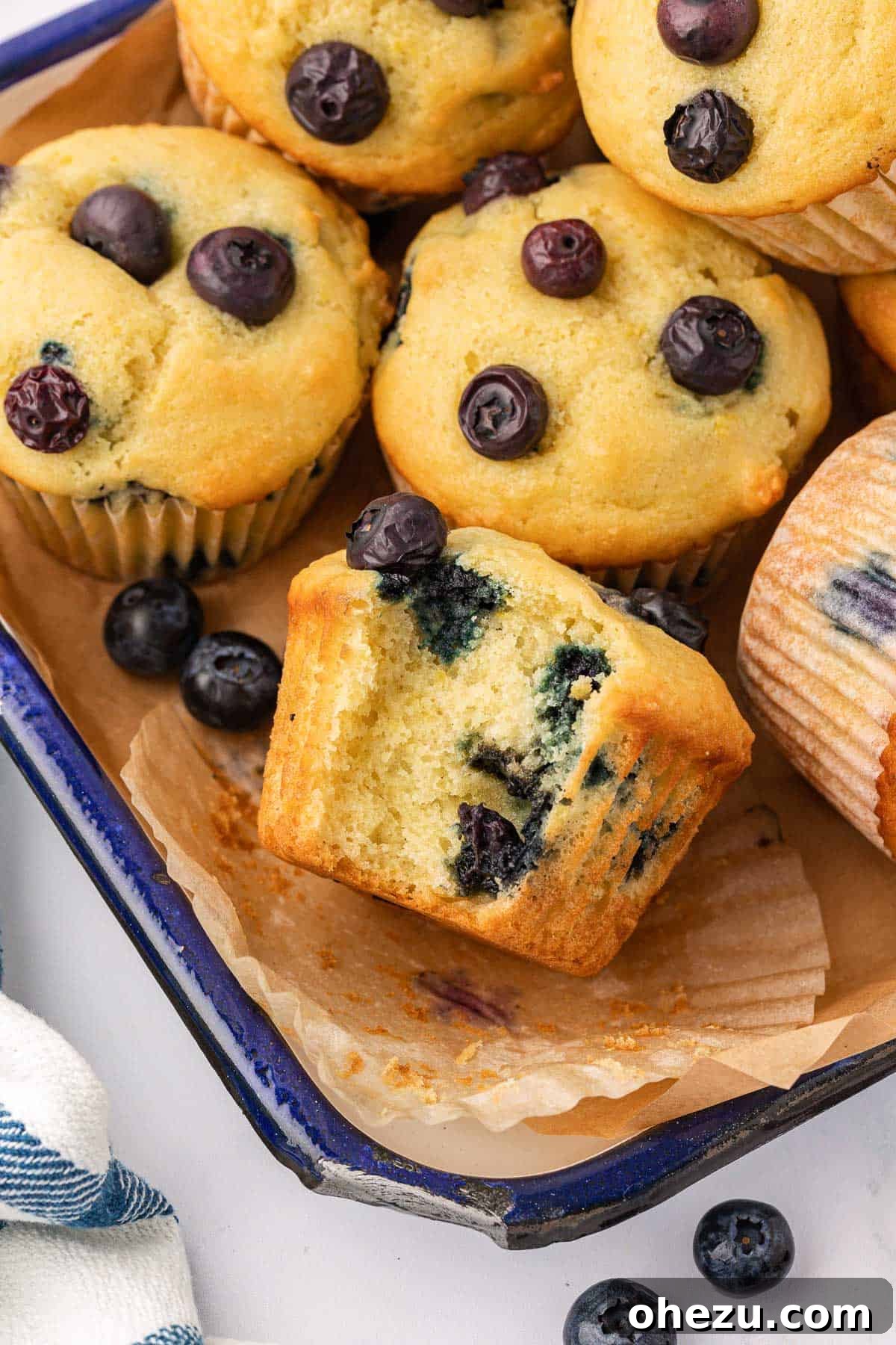 A perfectly baked sour cream blueberry muffin with a bite taken out, revealing its moist crumb and juicy blueberries.