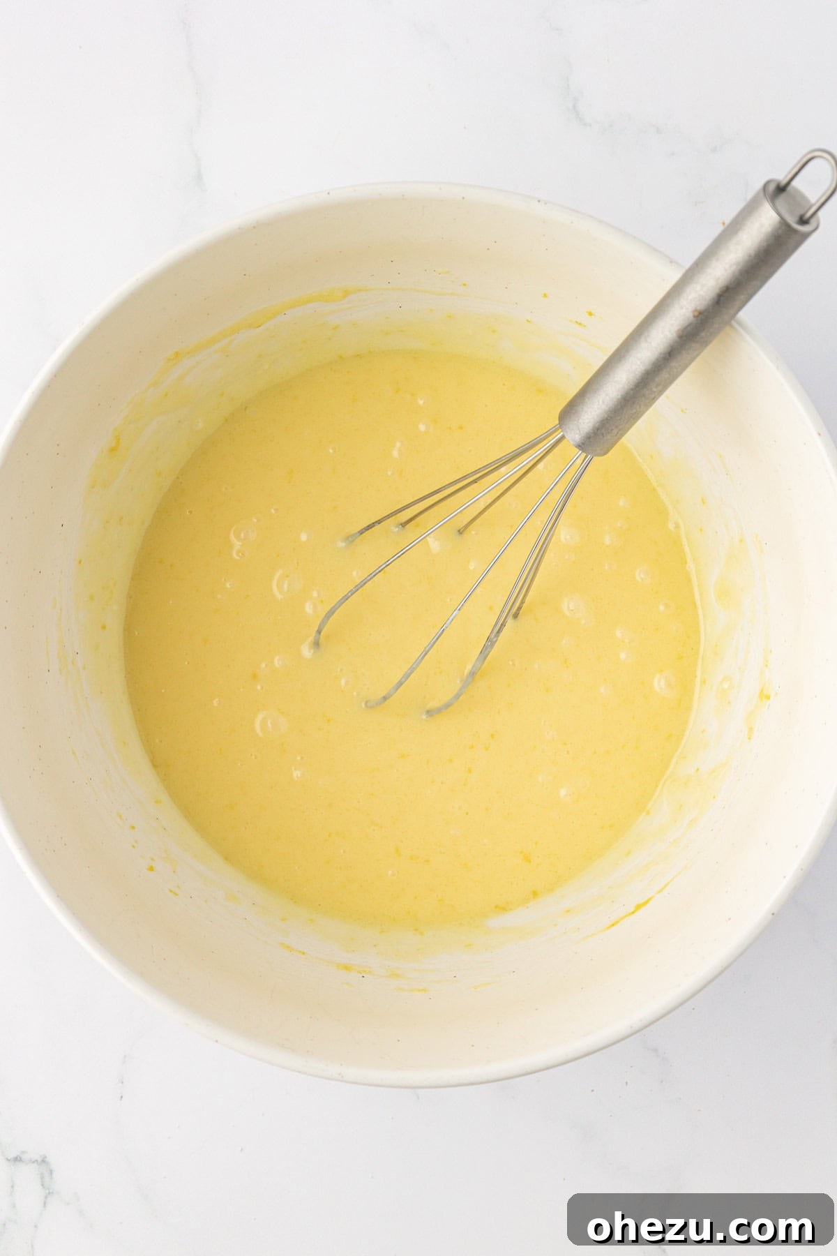Whisked wet ingredients in a bowl, creating a smooth, creamy mixture for the muffin batter.