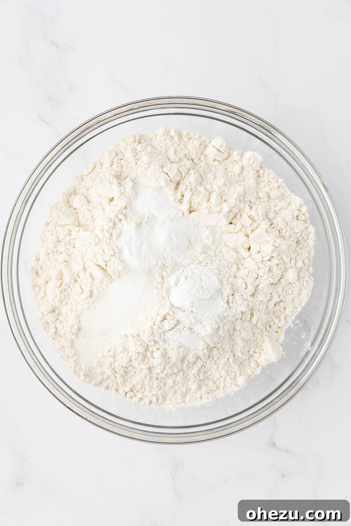Bowl filled with dry ingredients: flour, salt, baking powder, and baking soda, before mixing.
