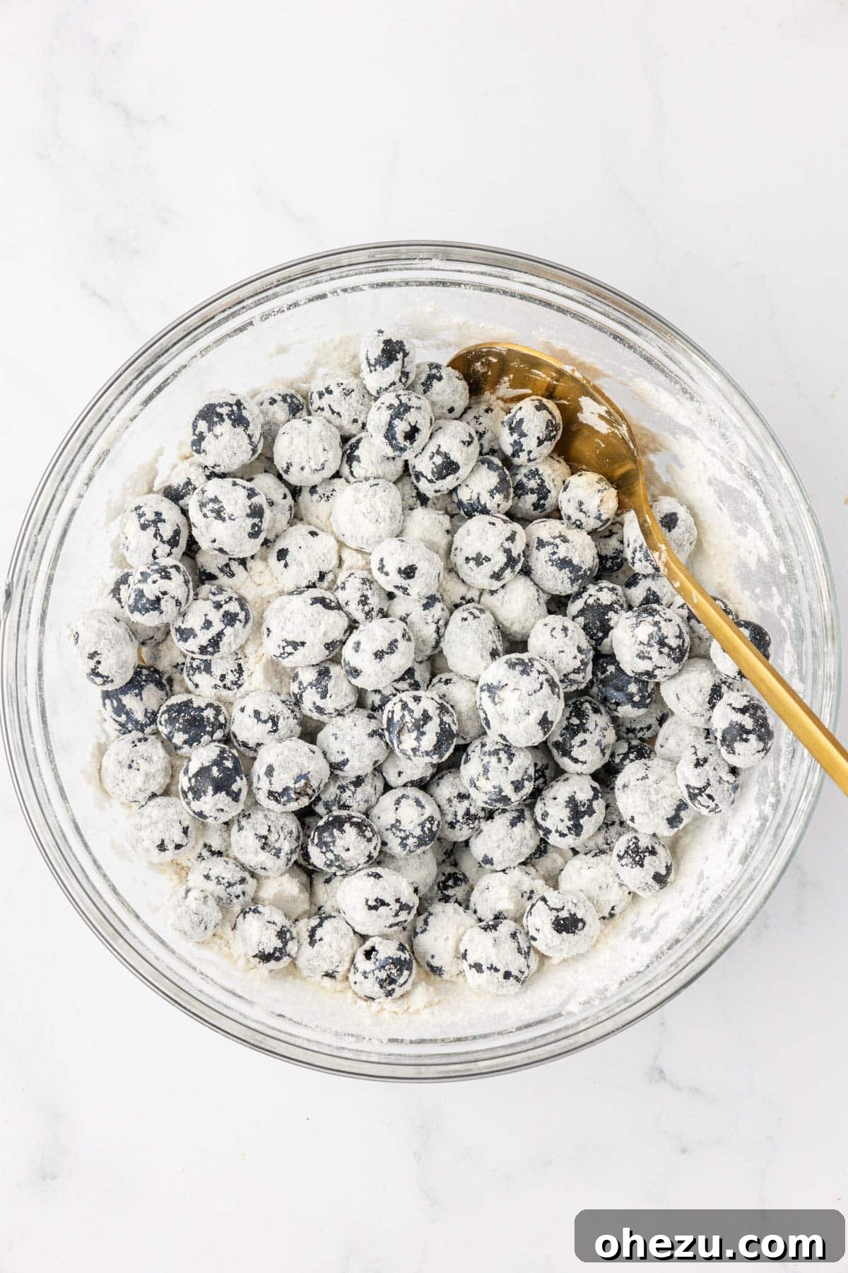 Fresh blueberries lightly tossed with a small amount of flour in a bowl, a trick to prevent them from sinking in muffin batter.