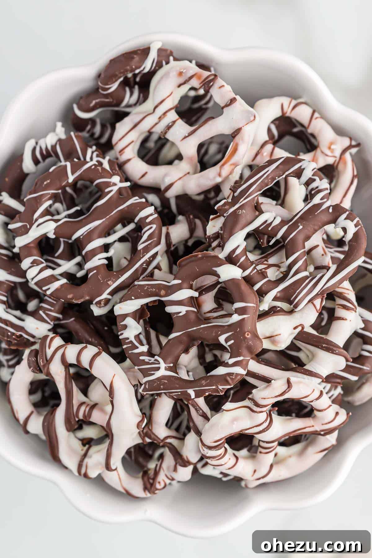 A decorative arrangement of various chocolate covered pretzels, showcasing different chocolate types and drizzling patterns, on a festive background.