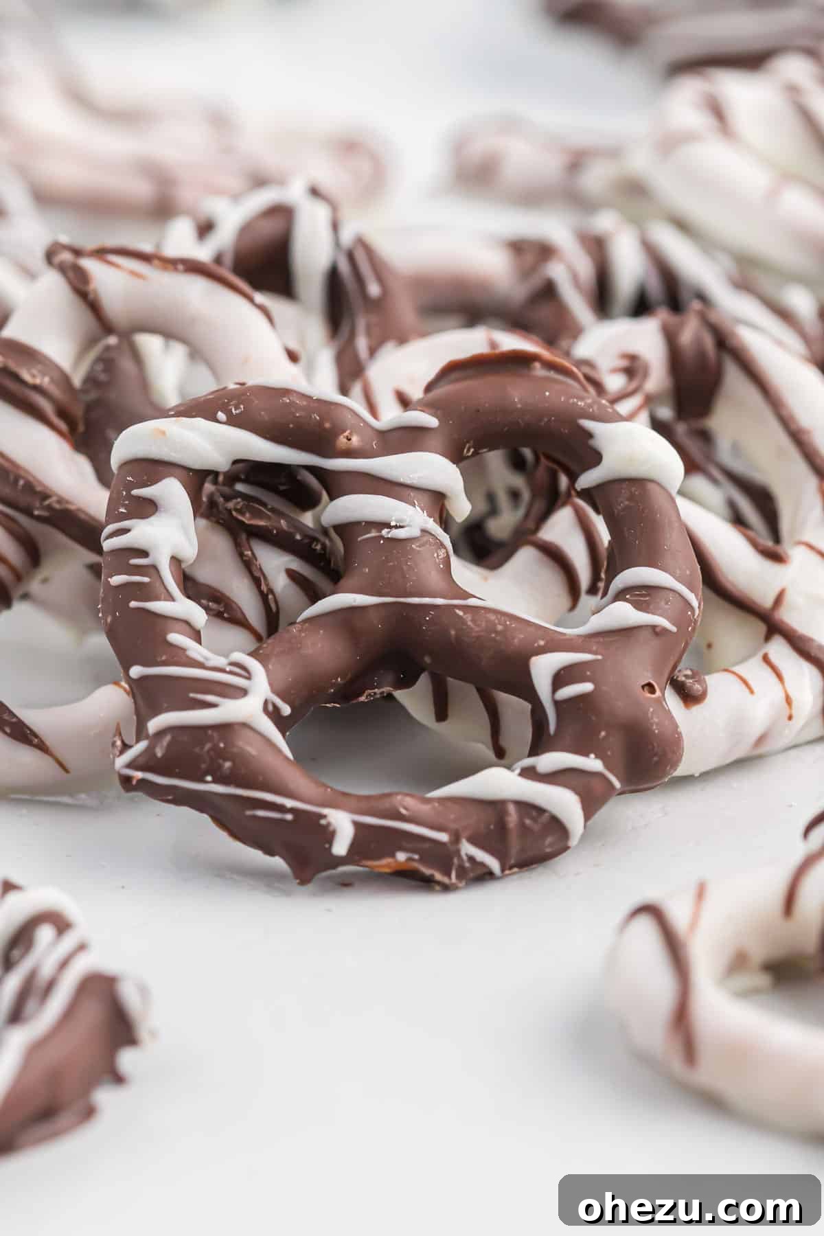 A single pretzel rod generously coated in dark chocolate and set on a piece of parchment paper, showcasing its appealing texture and rich color.