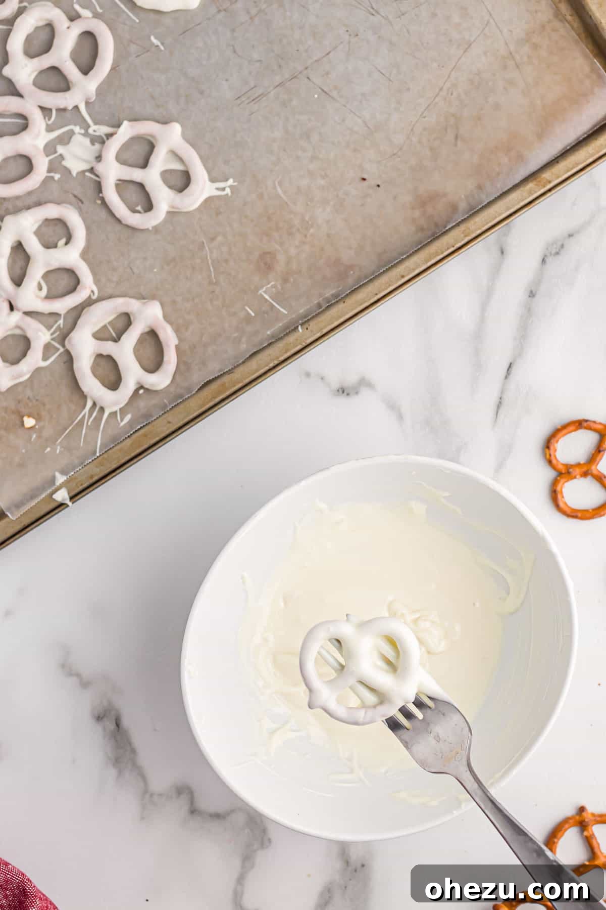 A mini pretzel completely coated in white chocolate, set on parchment paper, showing the smooth, clean finish.