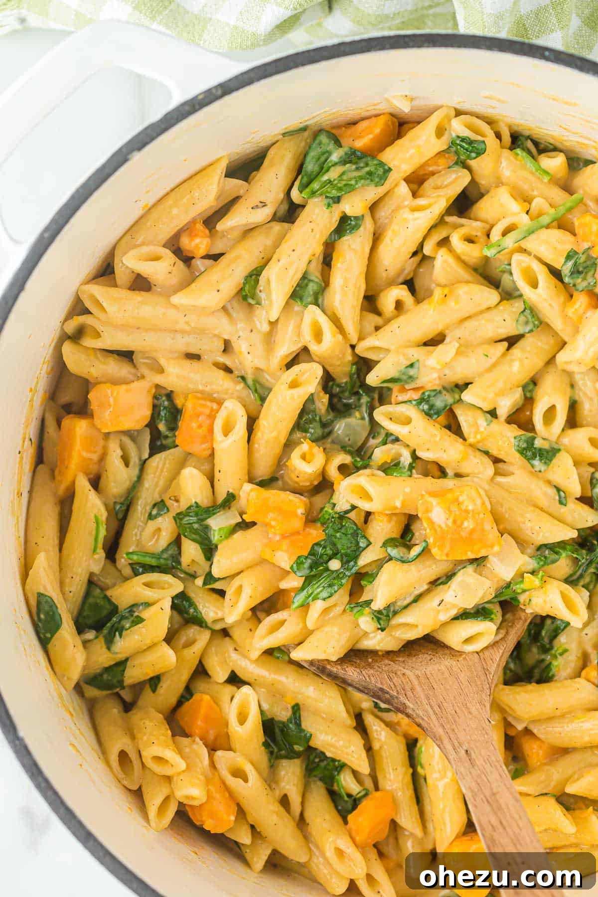 Velvet Sweet Potato Pasta 12 A serving of sweet potato pasta with visible chunks of sweet potato and vibrant spinach leaves.