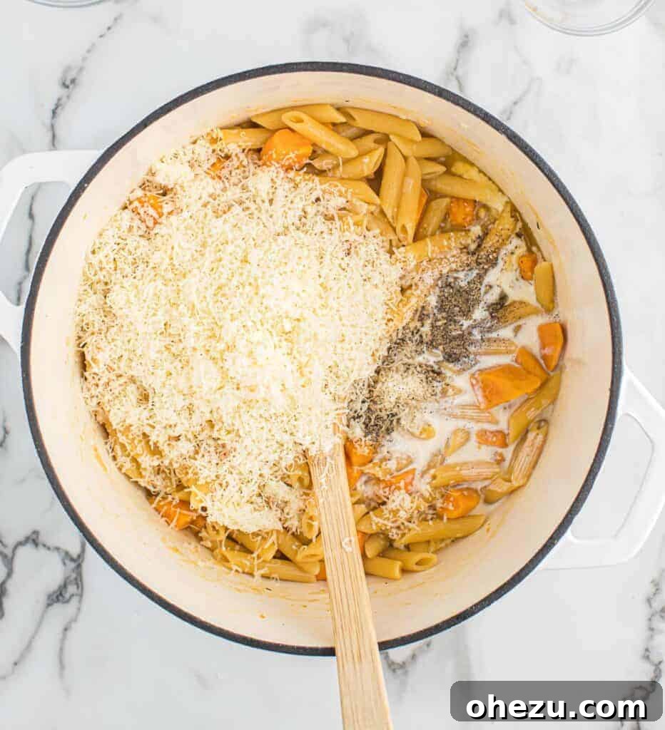Velvet Sweet Potato Pasta 7 Freshly grated Parmesan cheese being added to the cooked pasta in the pot.