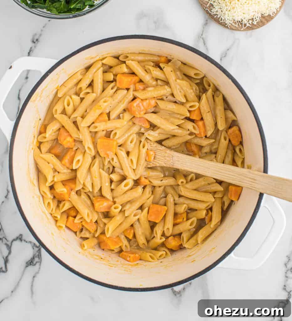 Velvet Sweet Potato Pasta 8 Sweet potato pasta being stirred to incorporate the creamy sauce, showing a thick and rich consistency.