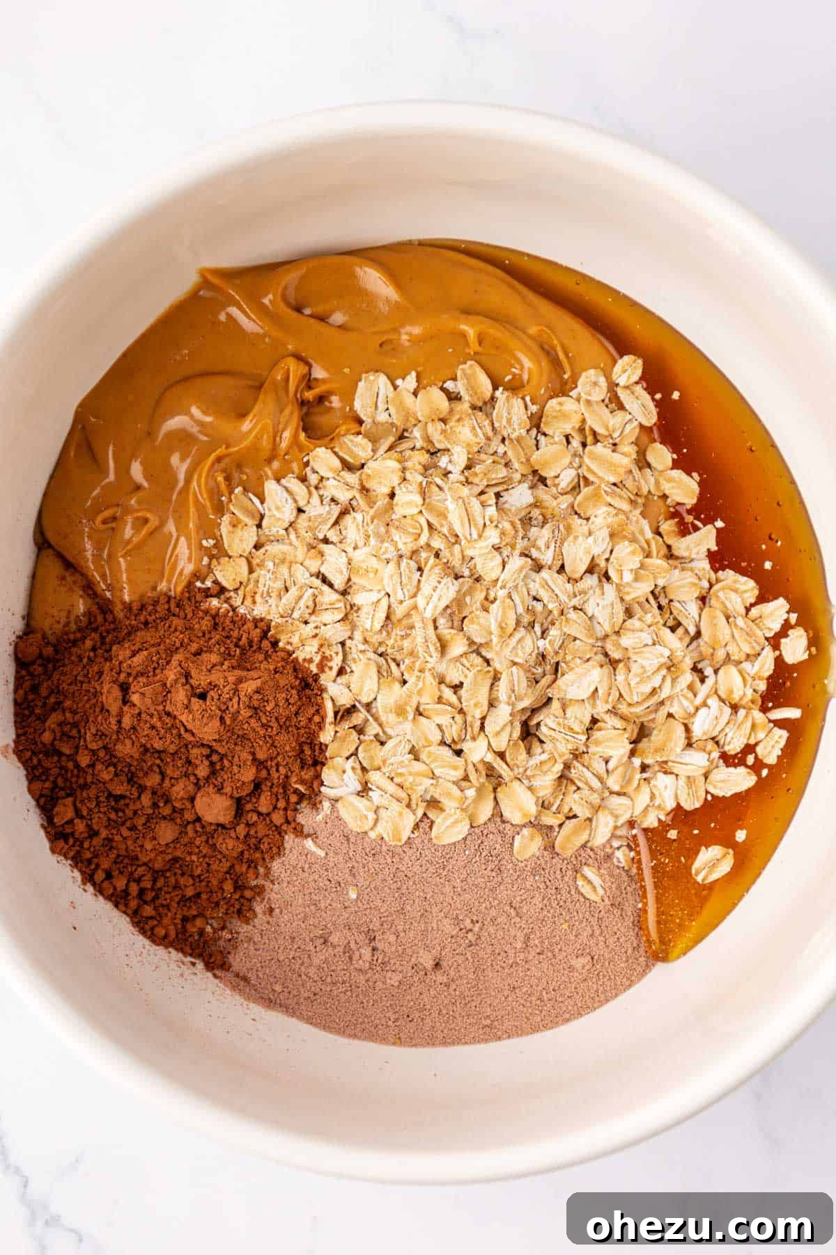 All the dry and wet ingredients for the chocolate protein bar base in a mixing bowl before stirring.