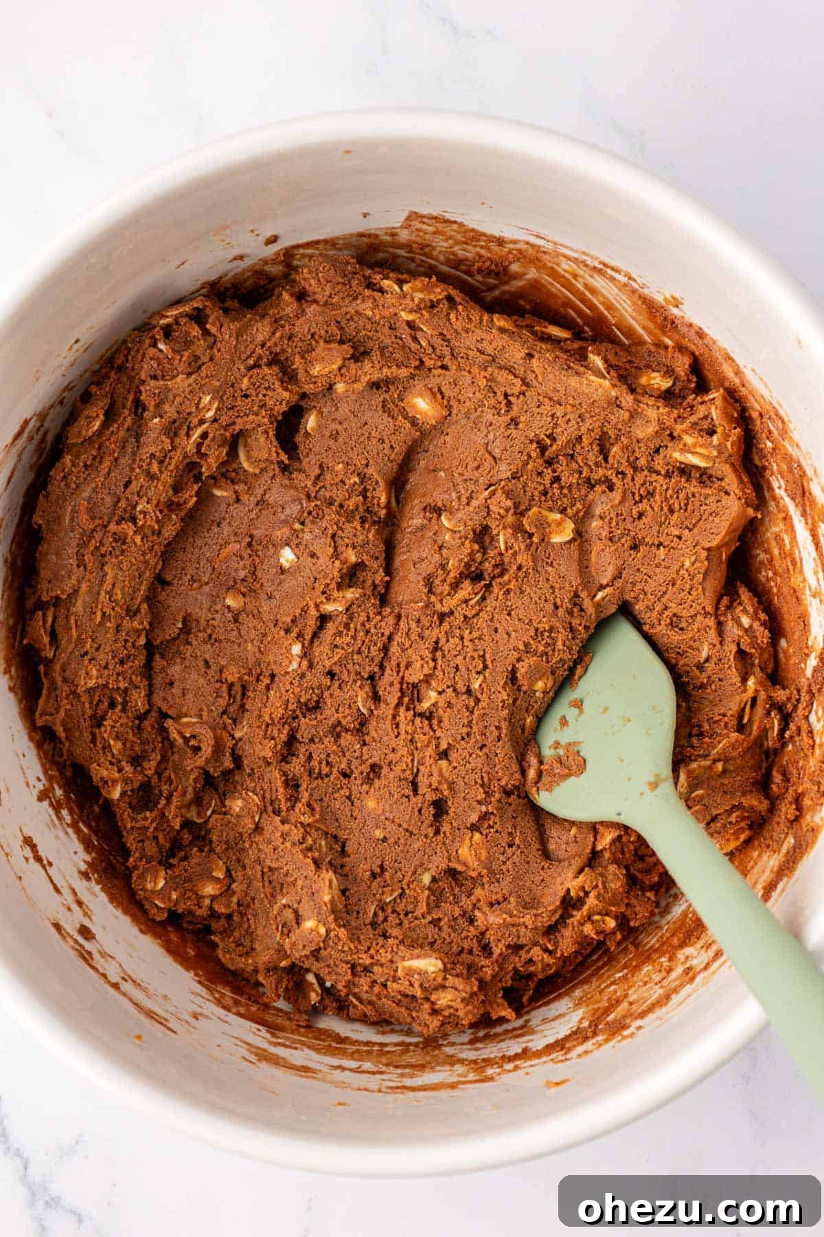 Thick, well-mixed chocolate protein bar batter in a mixing bowl, ready for the next step.