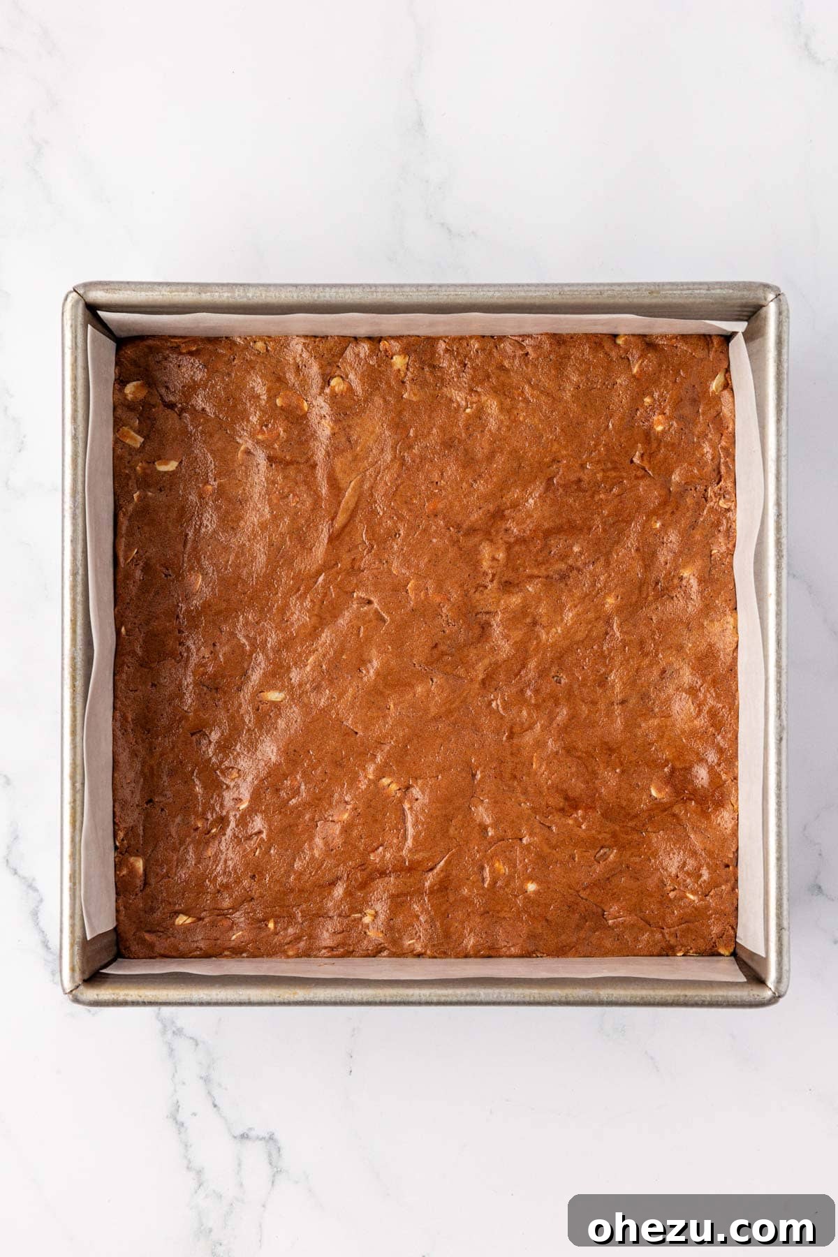 Chocolate protein bar mixture firmly pressed into an 8x8 inch baking dish lined with parchment paper.