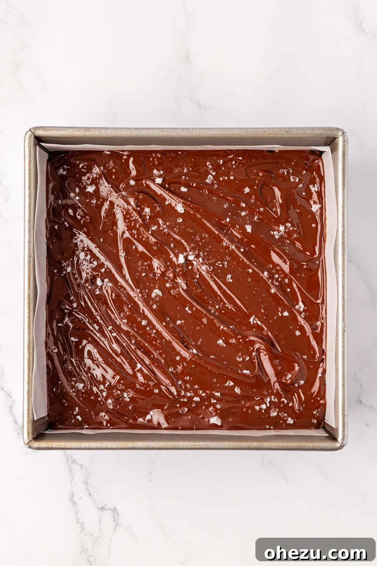 Melted chocolate topping on the protein bars, freshly sprinkled with flaky sea salt.