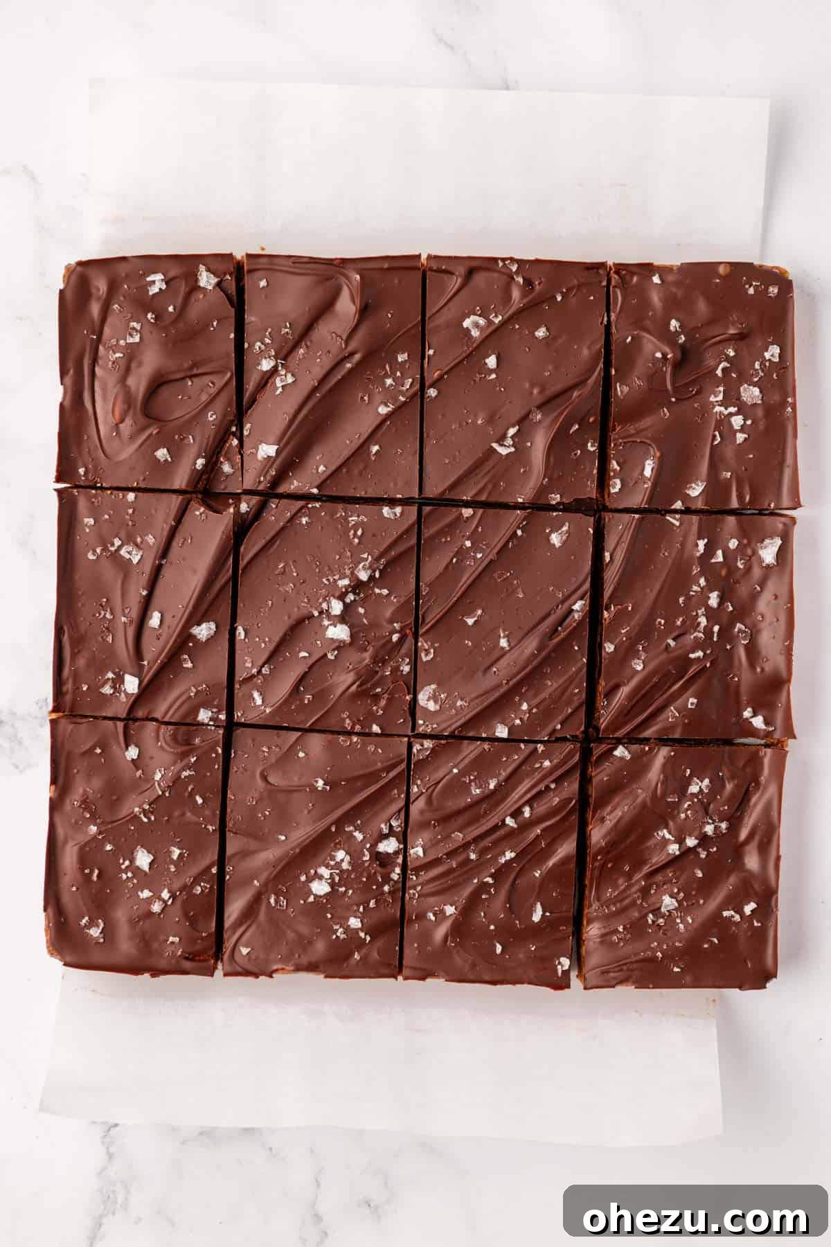 A batch of homemade chocolate protein bars, perfectly sliced into 12 even pieces, showcasing the base and chocolate topping.