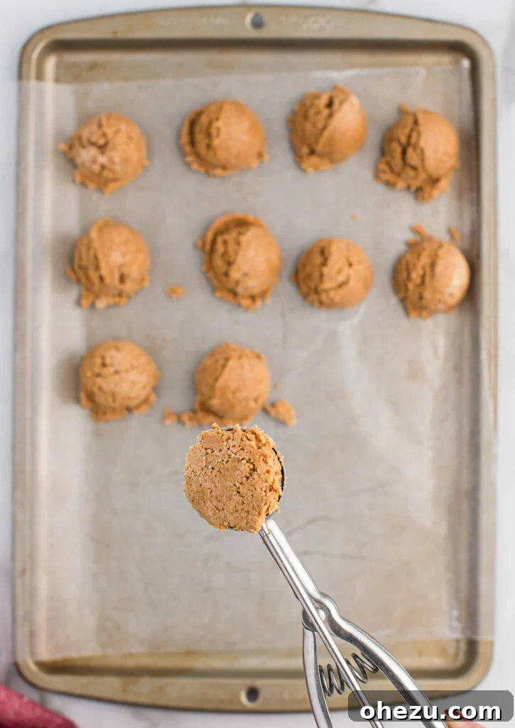 A mini cookie scoop filled with peanut butter ball mixture, ready to be rolled