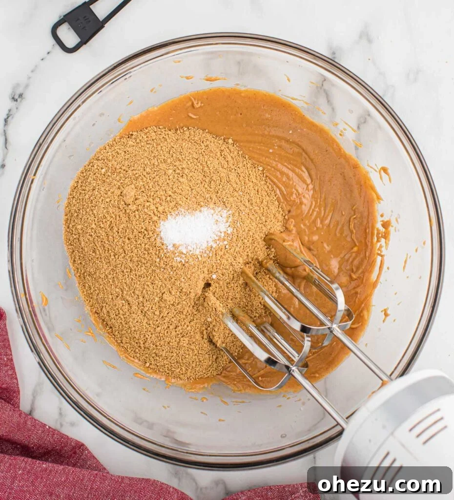 Adding graham cracker crumbs and salt to the mixed peanut butter and butter