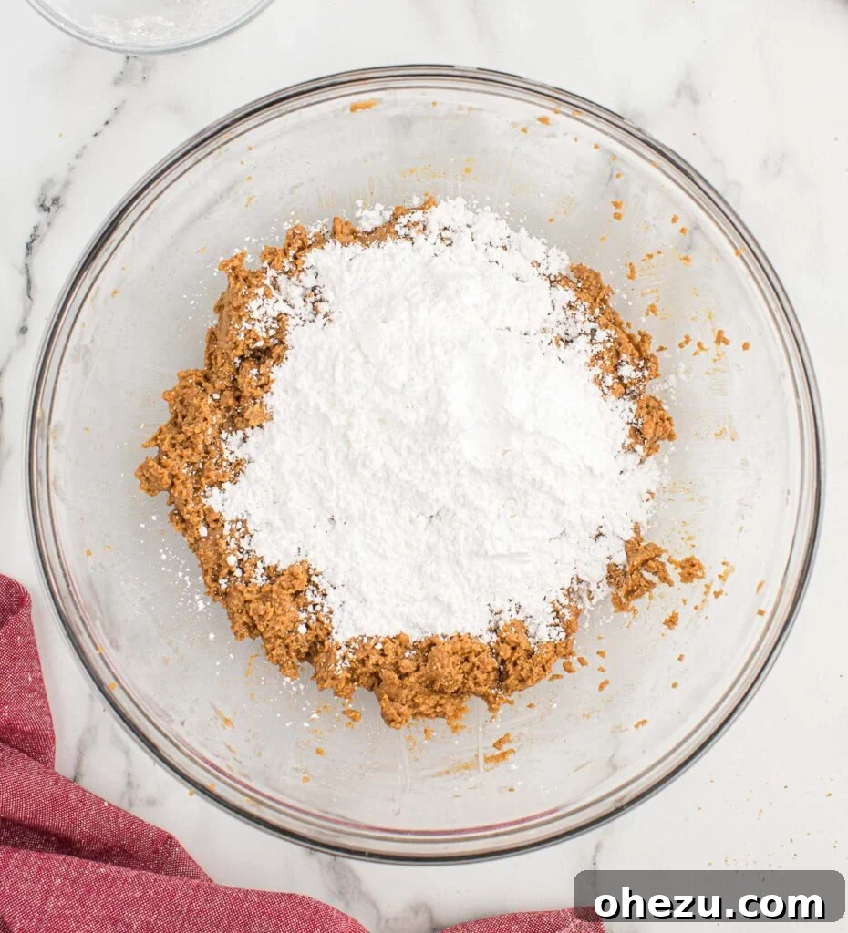 Adding powdered sugar to the peanut butter and graham cracker dough in a mixer
