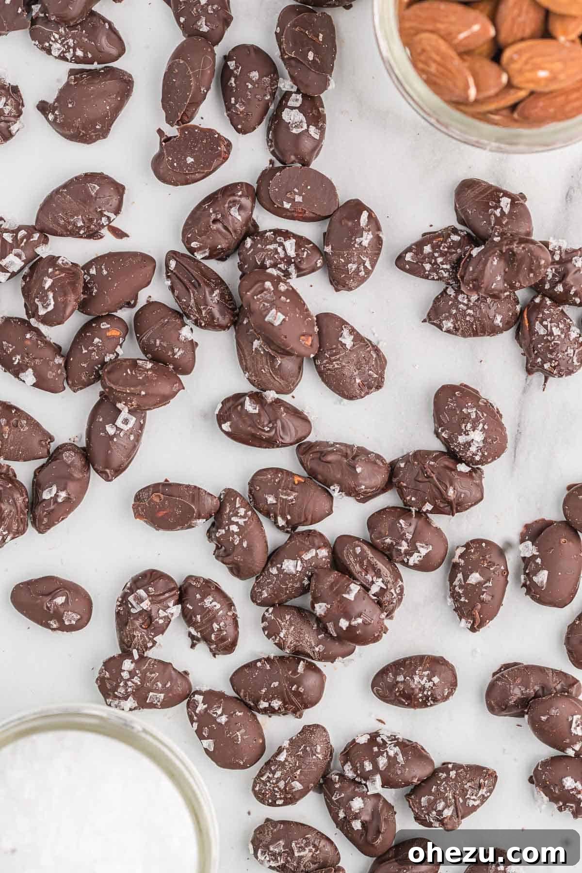 A pristine white bowl overflowing with a generous serving of homemade chocolate covered almonds, perfectly set and ready to be devoured.